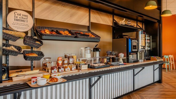 A breakfast buffet with bread, pastries, and beverages.