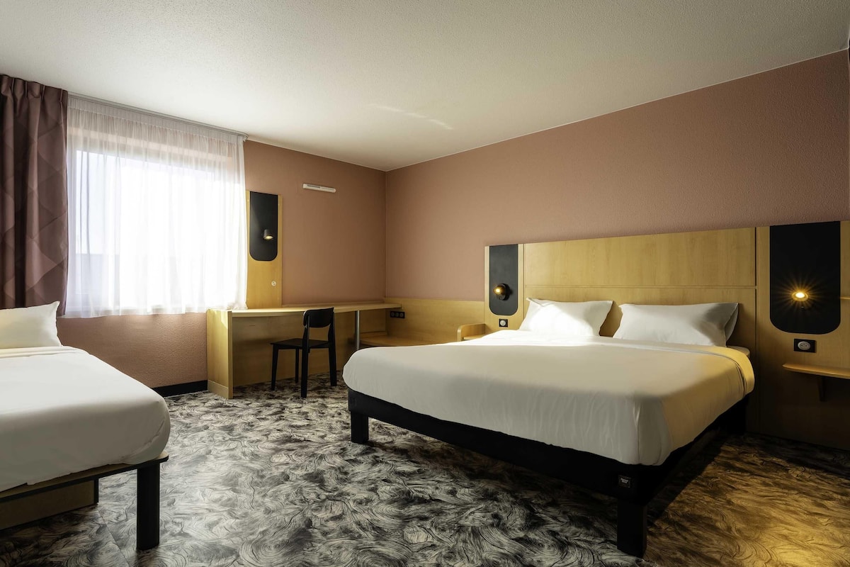 Ein Hotelzimmer mit Bett, Schreibtisch, Stuhl und einer Uhr an der Wand.
