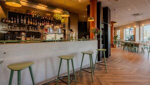 A bar area with stools, a bar counter, and a variety of bottles and glasses.