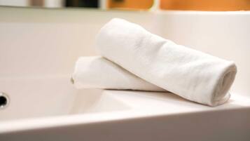 A white towel folded on a white sink.
