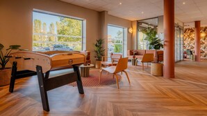 Un hall d’entrée spacieux avec une table de billard, des sièges confortables, de grandes fenêtres et un aménagement intérieur moderne.