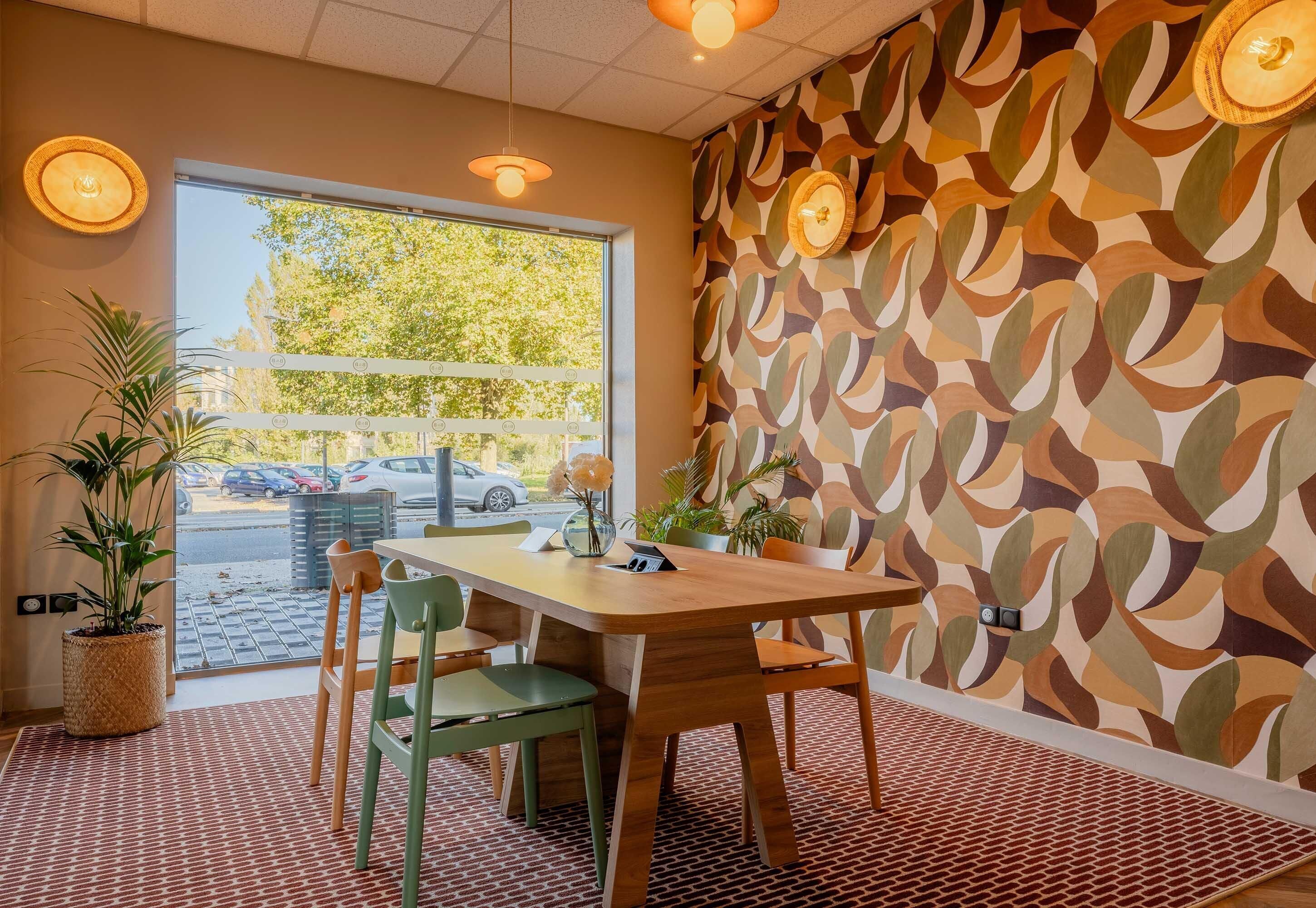 Un comedor con una mesa, sillas, plantas en macetas y un papel tapiz estampado.