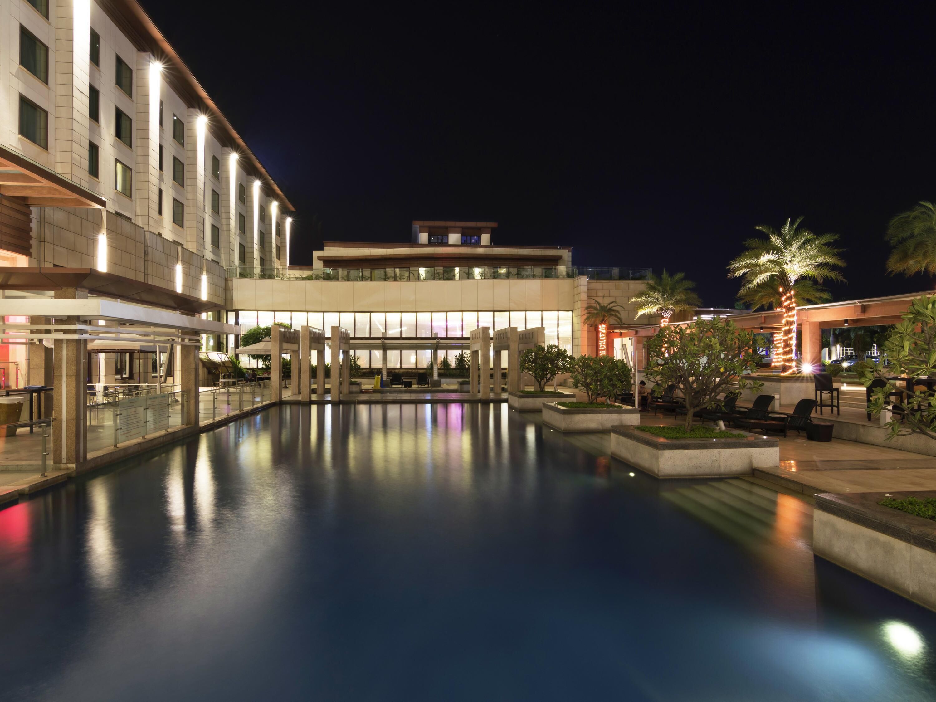 Un hôtel doté d’une piscine, d’un espace extérieur aménagé et d’une façade bien éclairée.