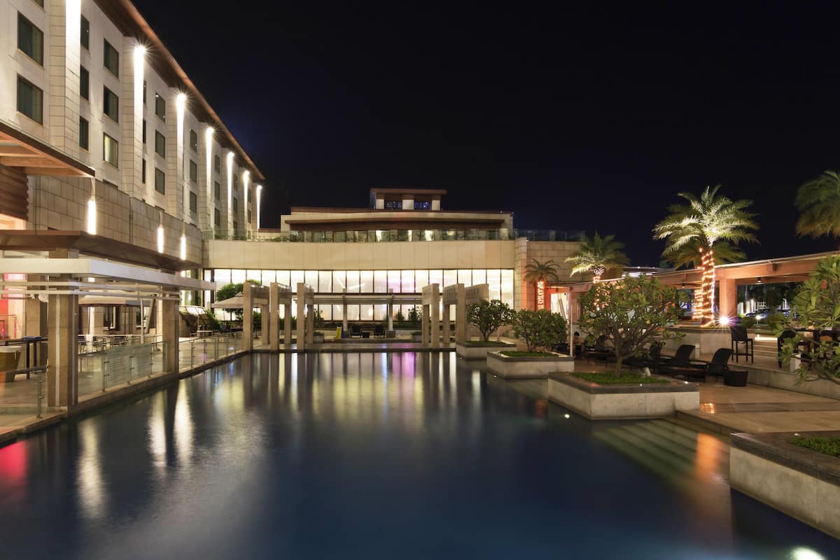 Ein Hotel mit Schwimmbad, Außenbereich zum Sitzen und einer gut beleuchteten Fassade.