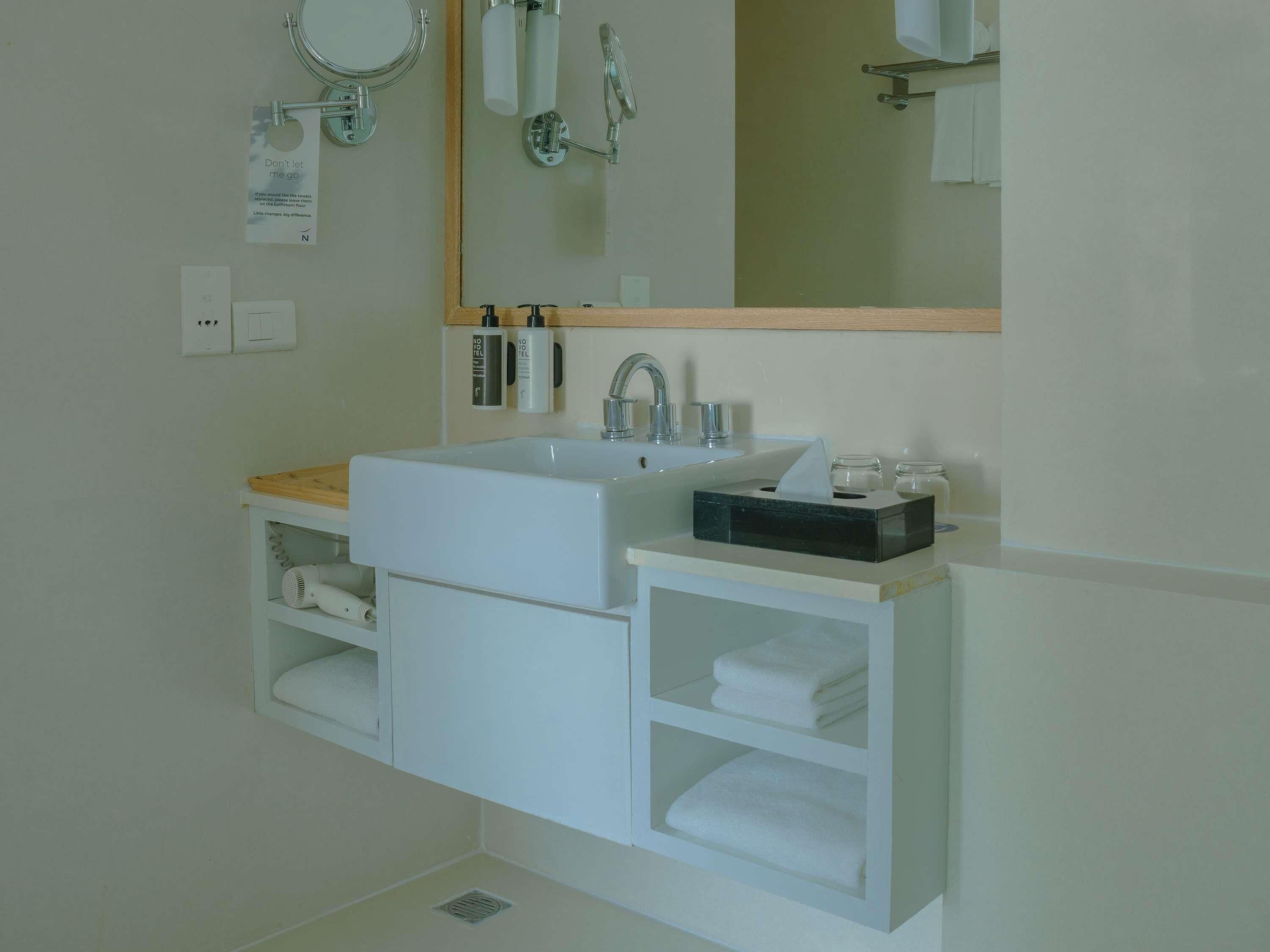 A modern bathroom with a large white sink, a mirror, and a towel rack.