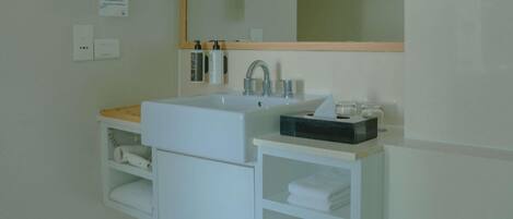 A modern bathroom with a large white sink, a mirror, and a towel rack.