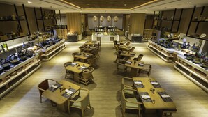 Un restaurante moderno con una barra central, mesas y sillas de madera, y estantes con vajilla y cristalería.