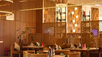A restaurant with wicker furniture, pendant lighting, and a wooden interior.