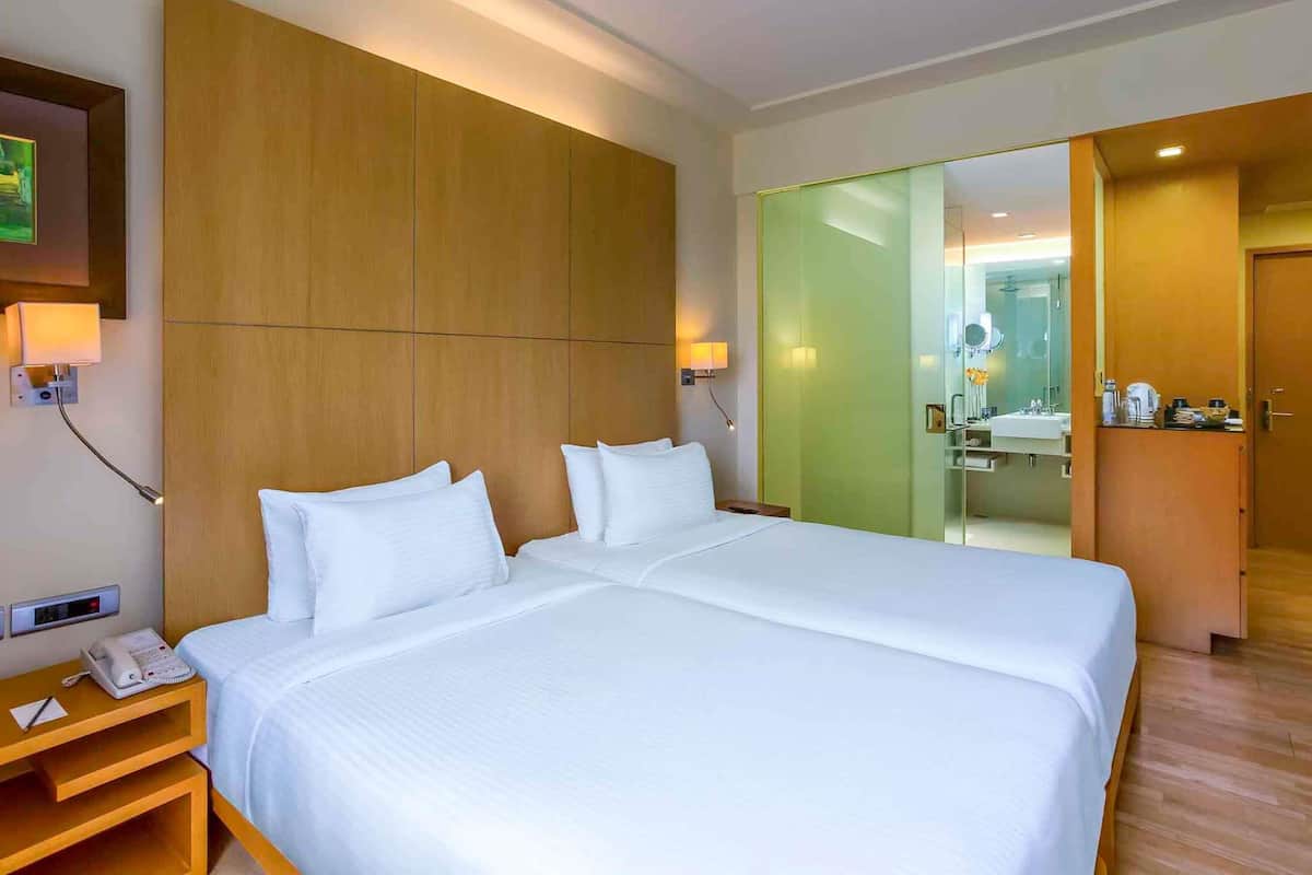 Une chambre d’hôtel avec un grand lit, des lampes de chevet, un téléphone et un miroir.
