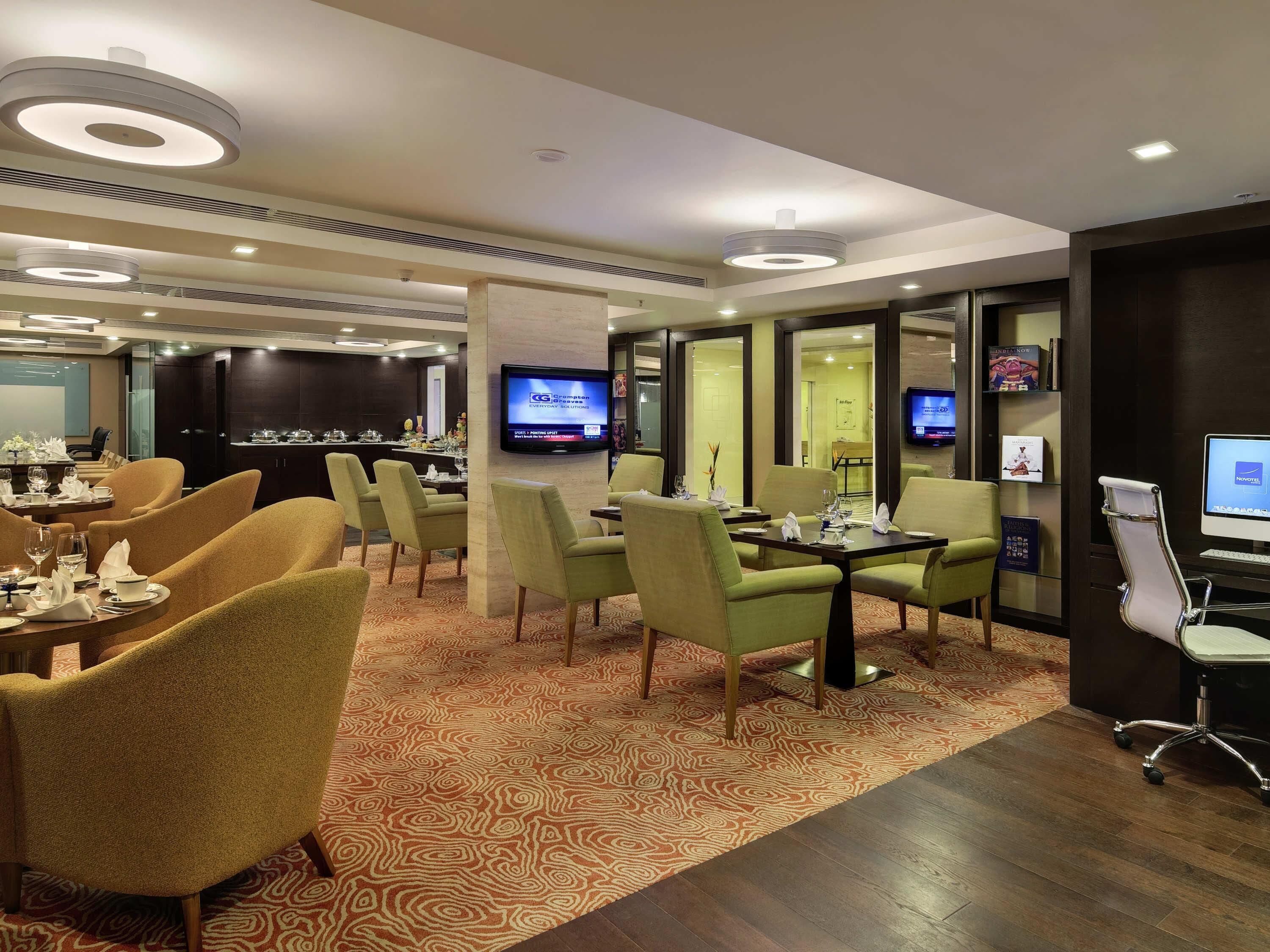 Zona de dinar d'un hotel amb diverses taules, caires i una pantalla de televisió.