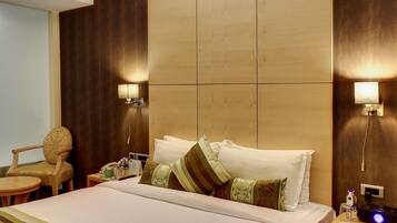 A hotel room with a large bed, two bedside tables, a chair, and wall-mounted lamps.
