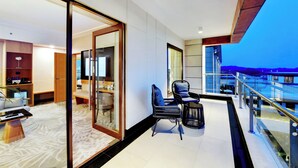 Habitación de hotel moderna con balcón, zona de comedor y vistas a la montaña.