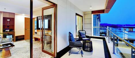 A modern hotel room with a balcony, a dining area, and a view of the mountains.