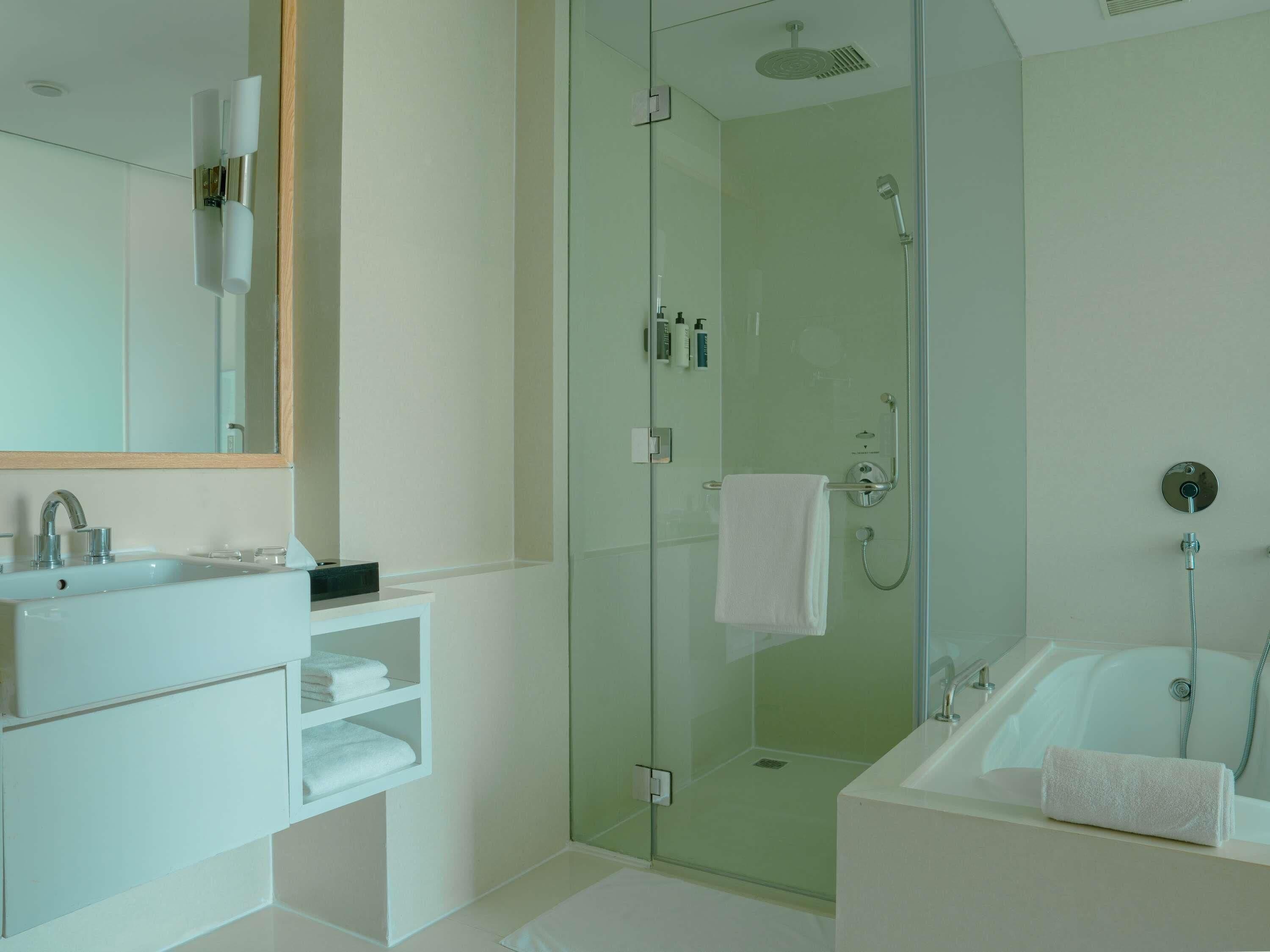 Un bagno moderno con doccia vetro, vasca da bagno indipendente e mobile lavabo con specchio e lavandino.