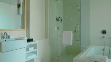 Un bagno moderno con doccia vetro, vasca da bagno indipendente e mobile lavabo con specchio e lavandino.
