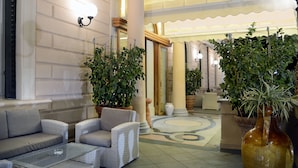 En lobby med sofaer, plantekasser og flisegulv.