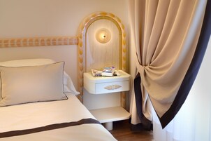 A hotel room with a bed, a bedside table with a magazine, and a curtain.