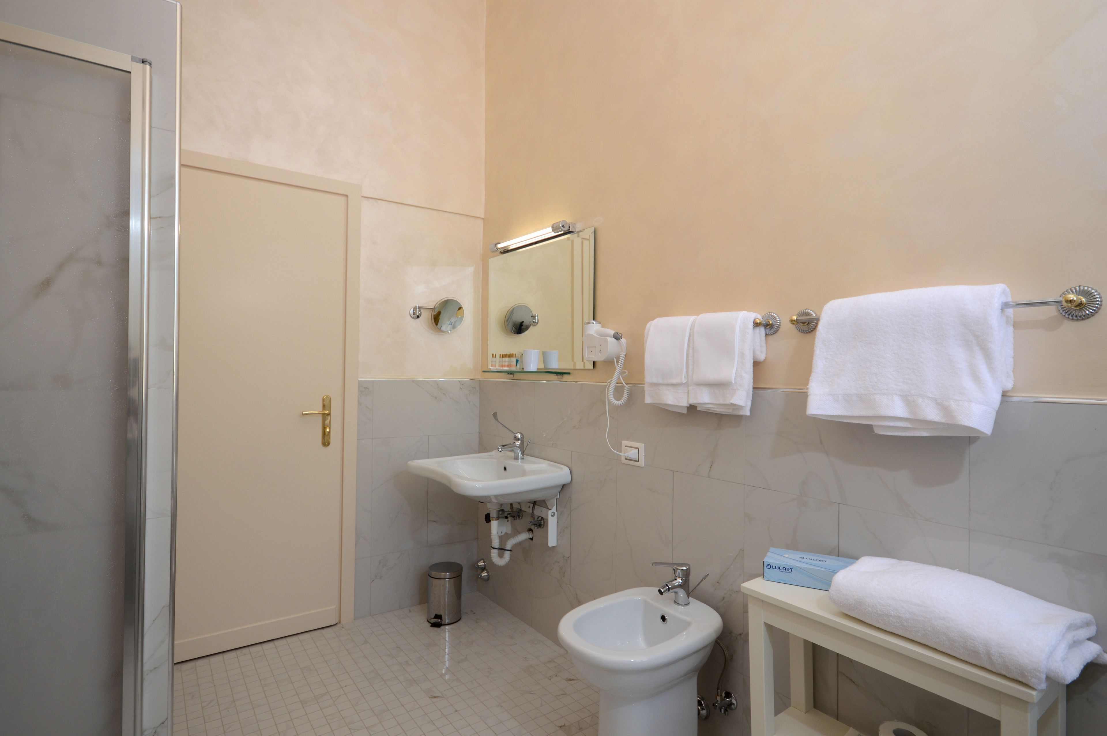 Un baño con lavamanos, bidé y toallero.