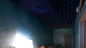 Et værelse med stjernehimmel, en liggestol, et natbord og en lampe.