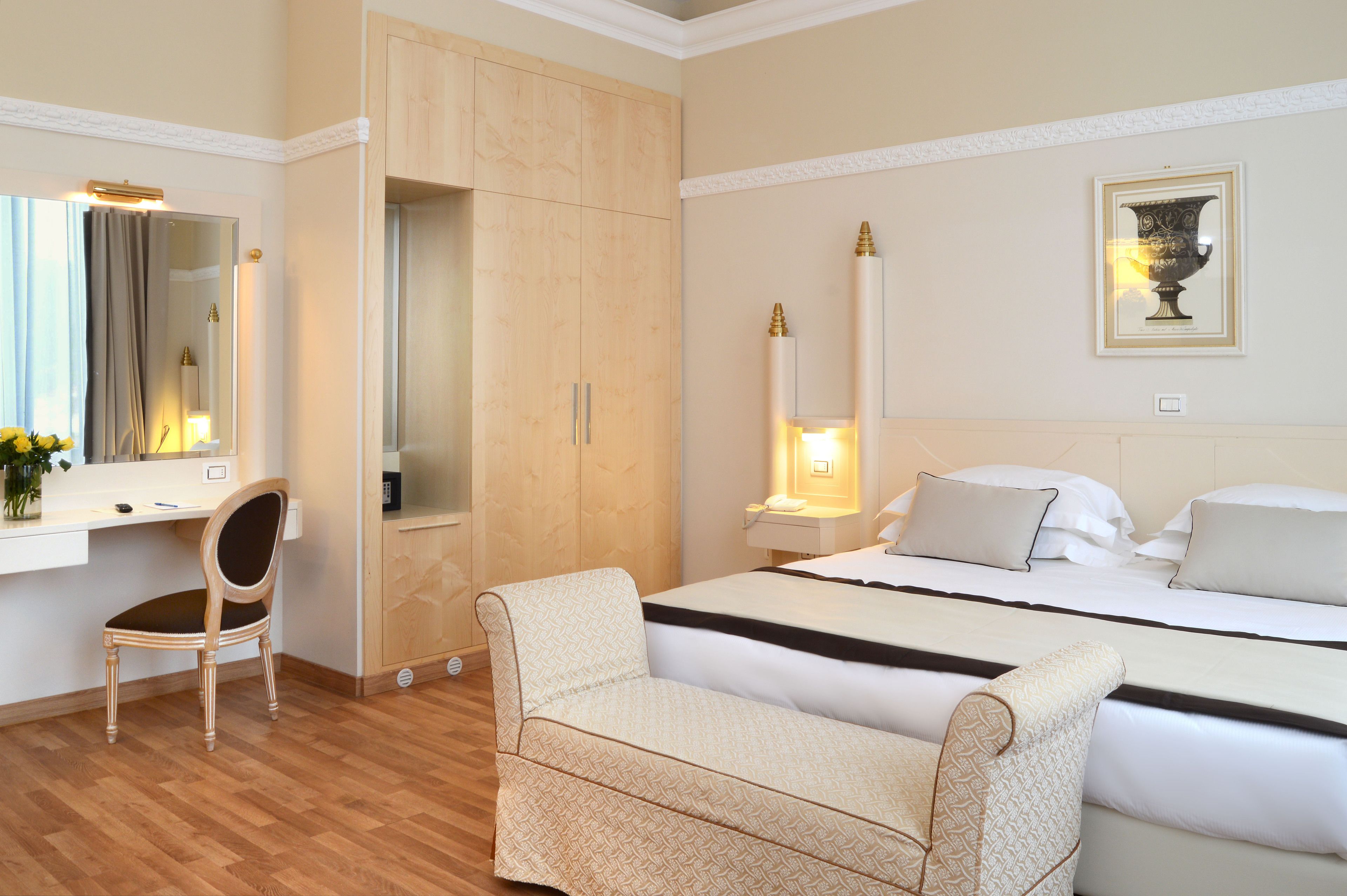 A hotel room with a bed, a desk, a chair, and a wardrobe.