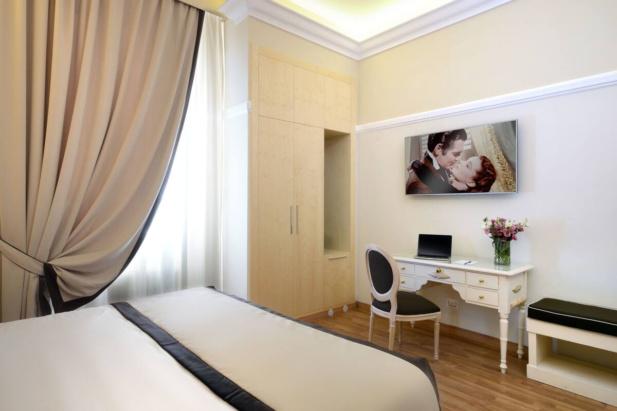 Ein Hotelzimmer mit Bett, Schreibtisch, Stuhl, Fernseher und Kleiderschrank.
