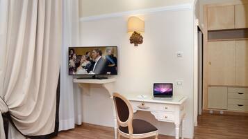 Habitación de hotel con escritorio, silla, televisión y armario.