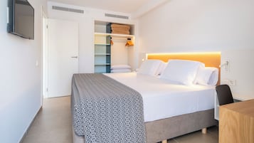 A modern hotel room with a neatly made bed, a built-in wardrobe, and a flat-screen TV mounted on the wall.