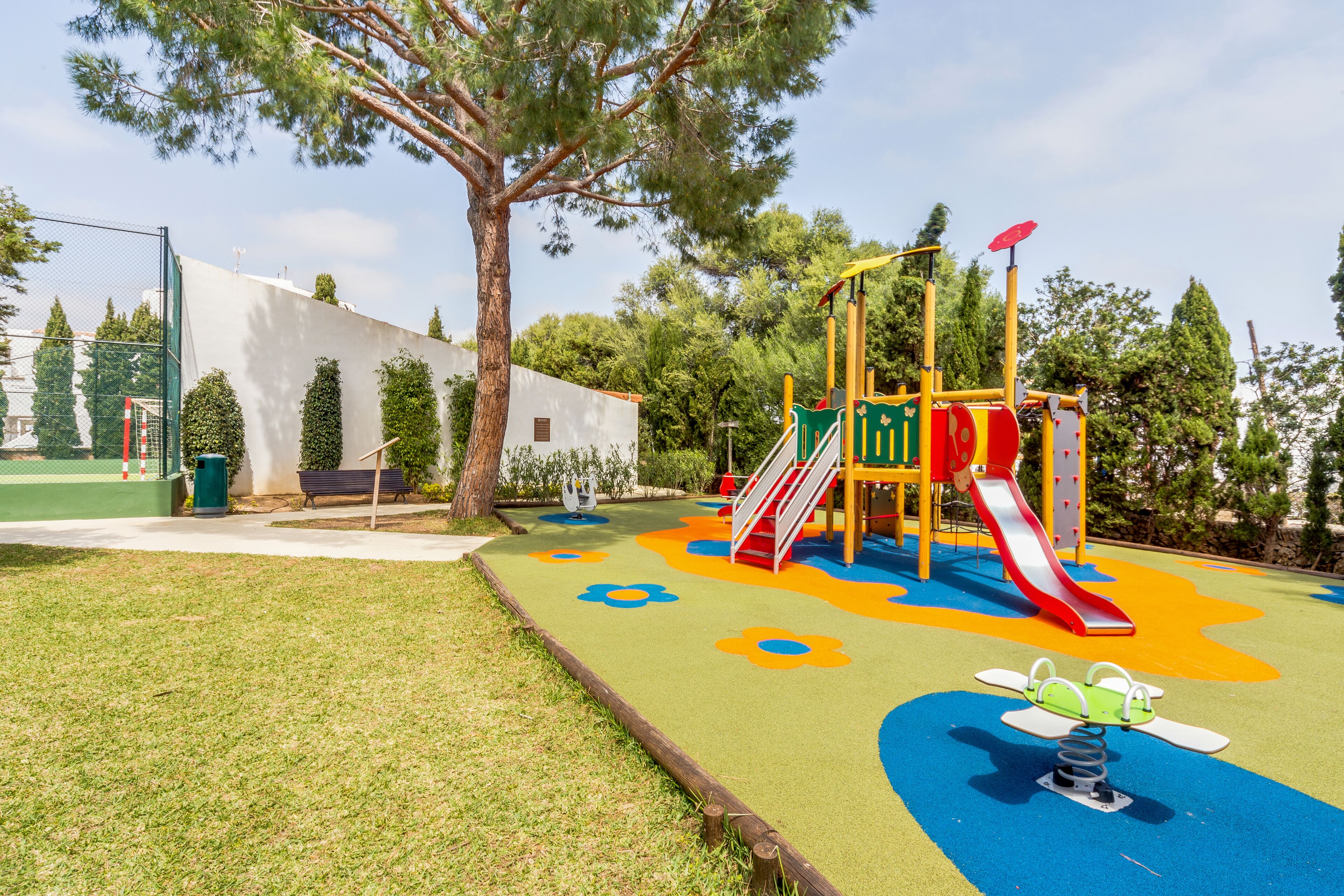 A playground with a slide, climbing structures, and a colorful play area.