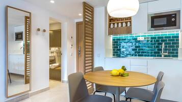 Una cocina moderna con una mesa redonda de madera, sillas grises y un microondas encima.