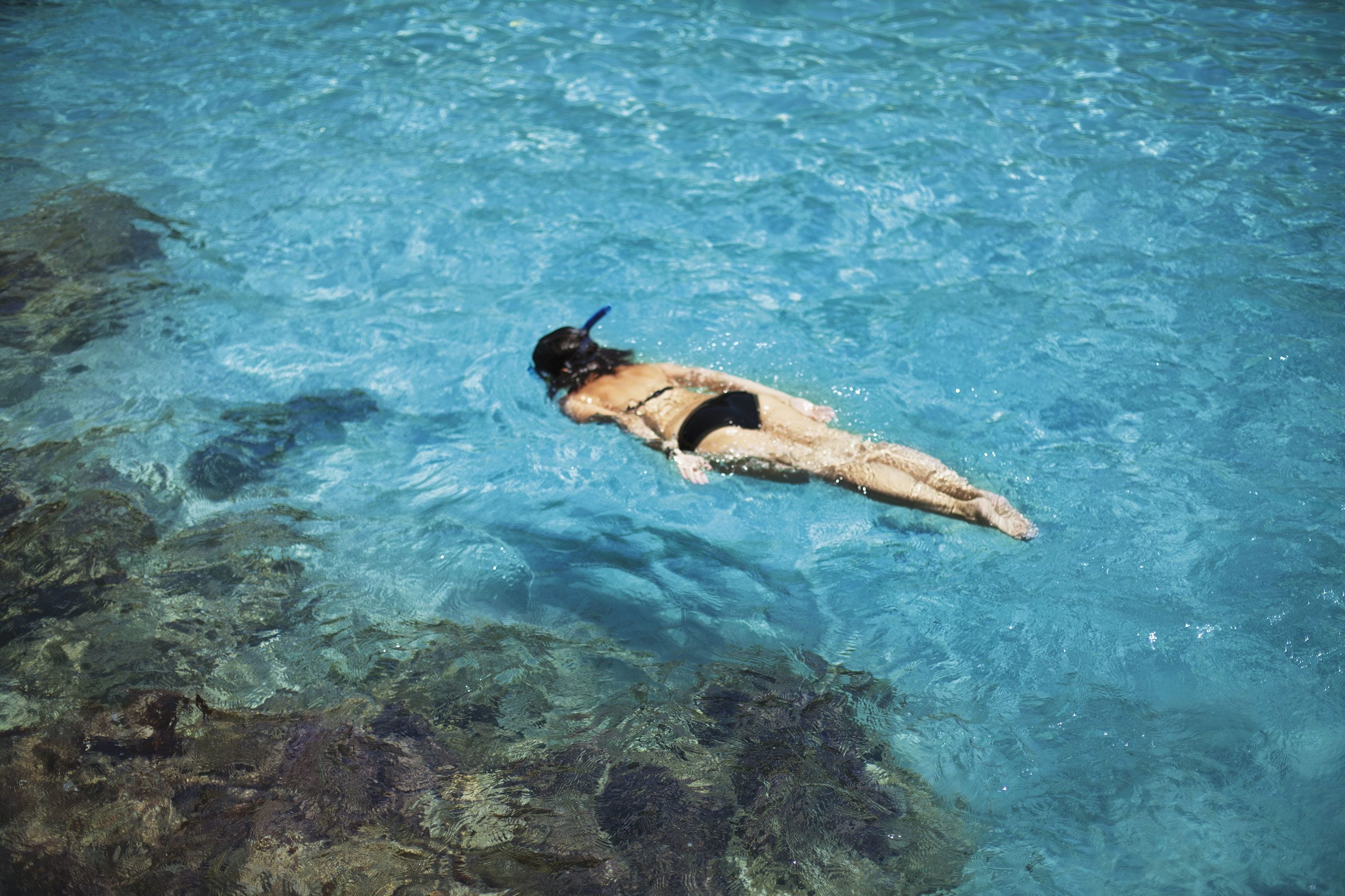 Eine Person schwimmt in klarem, blauem Wasser.
