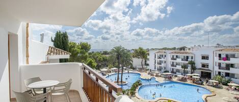 A balcony with a view of a swimming pool complex, including multiple pools and lounge areas.