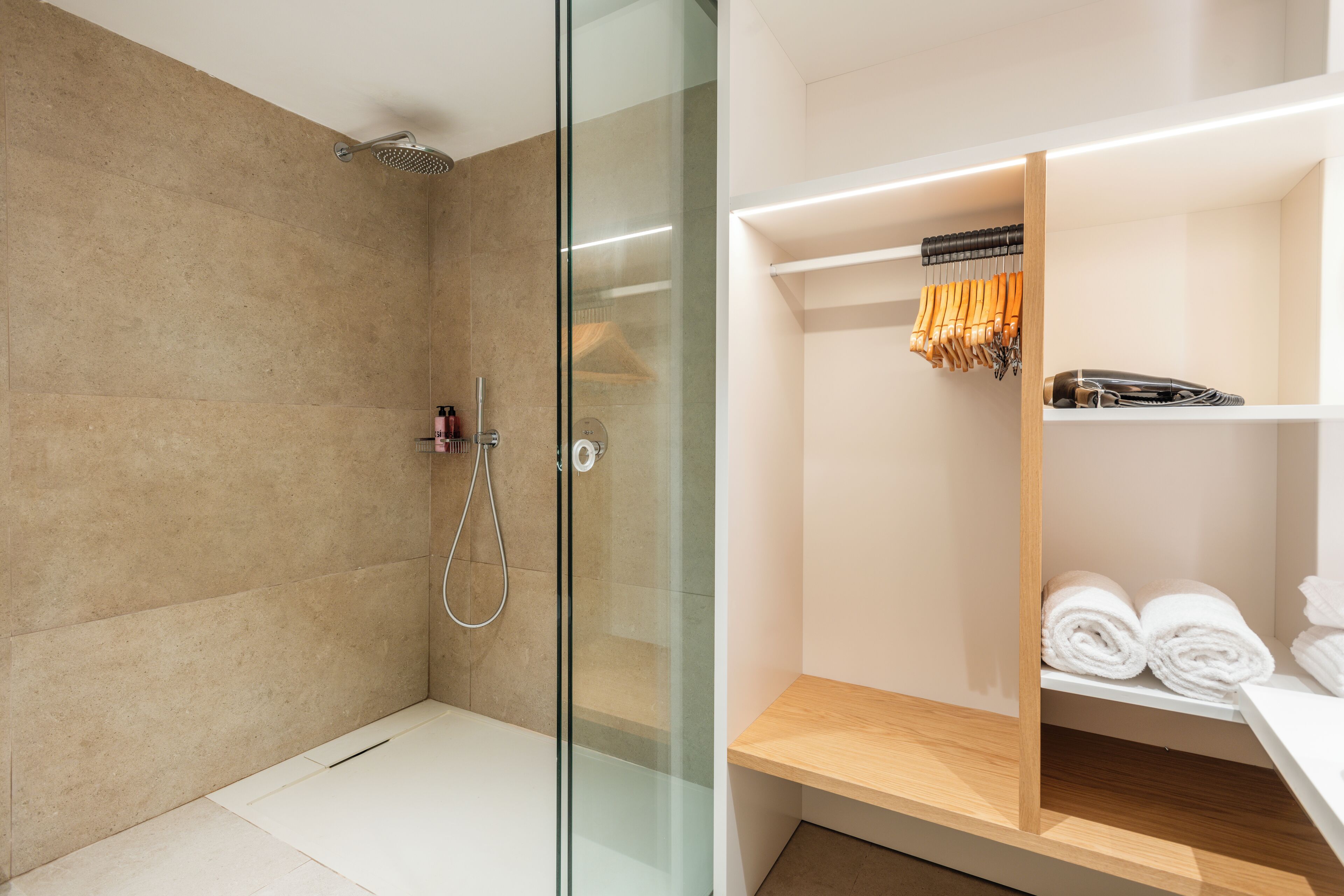 Une salle de bain moderne avec une douche à parois de verre, un meuble-lavabo en bois et des serviettes soigneusement pliées.