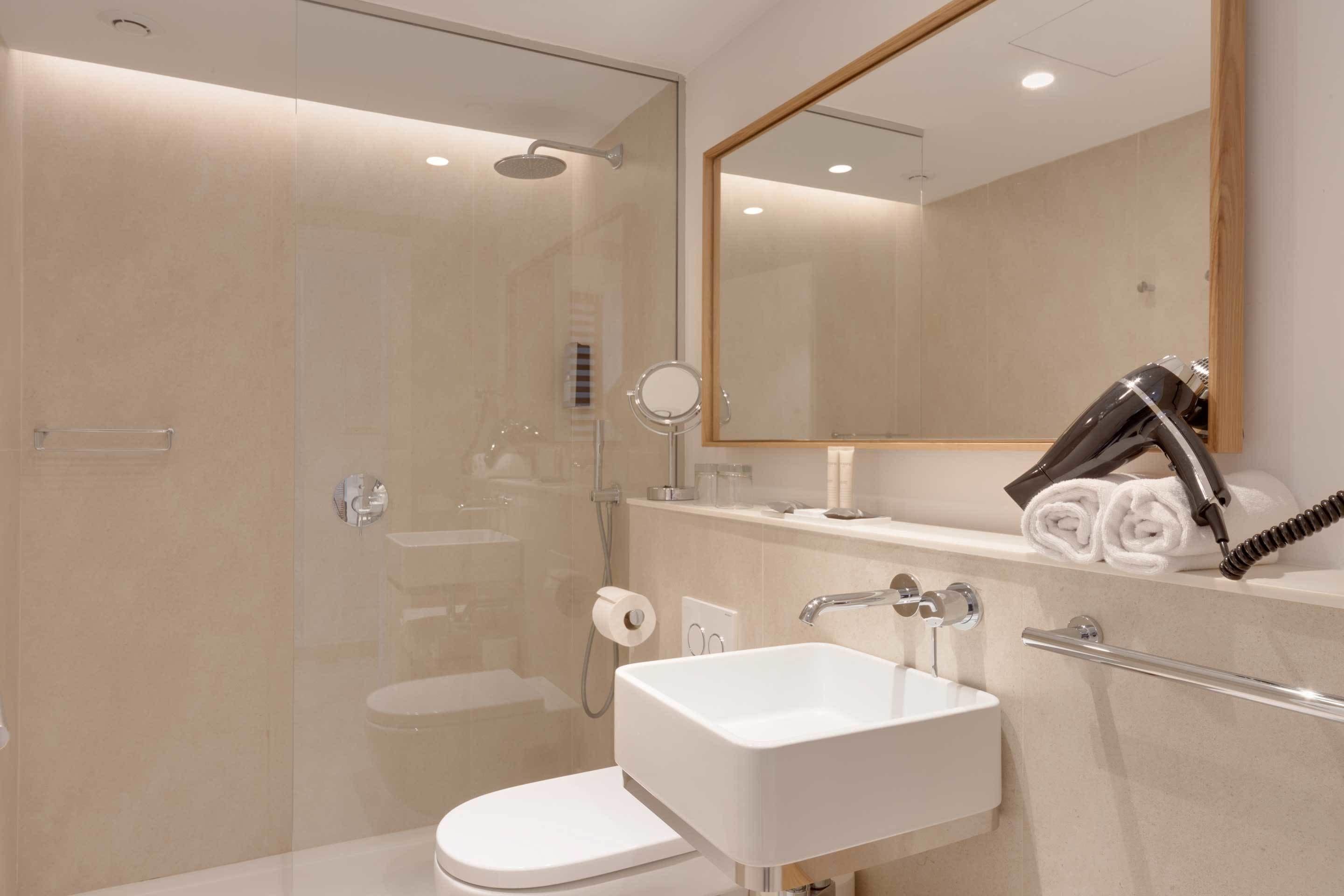 A modern bathroom with a glass-enclosed shower, a white sink, and a mirror above it.