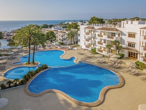 Un complexe hôtelier doté d’une grande piscine, de chaises longues et offrant une vue sur la mer.