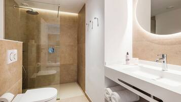 Un baño moderno con ducha de vidrio, lavamanos blanco y retrete.