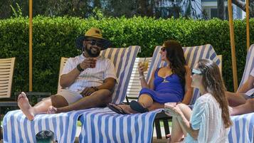 Zona junto a la piscina con sillones de descanso y sombrillas.