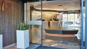 A modern hotel reception area with a glass entrance, a reception desk, and a seating area. - AC Hotel by Marriott, Manchester Salford Quays (Salford)