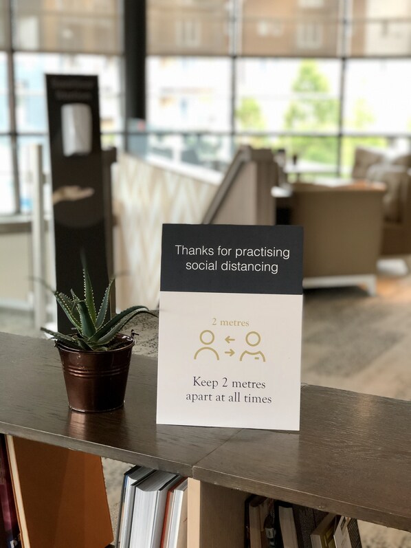 A sign on a counter thanking for practicing social distancing, with a 2 metres distance symbol. - AC Hotel by Marriott, Manchester Salford Quays (Salford)