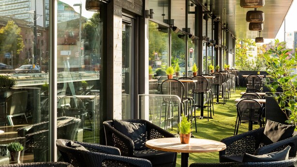 An outdoor seating area with wicker furniture and potted plants, overlooking a cityscape. - AC Hotel by Marriott, Manchester Salford Quays (Salford)