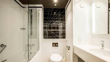 Un baño moderno con ducha de vidrio, inodoro blanco y lavamanos con espejo.