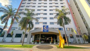 A Comfort Hotel building with a modern design, featuring a large entrance and palm trees in the foreground.