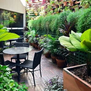 A patio area with a round table and chairs, surrounded by potted plants and a wooden fence. - Comfort Hotel Goiania (Goiania)