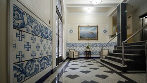 Un couloir orné de carreaux décoratifs, un escalier et un tableau encadré accroché au mur.