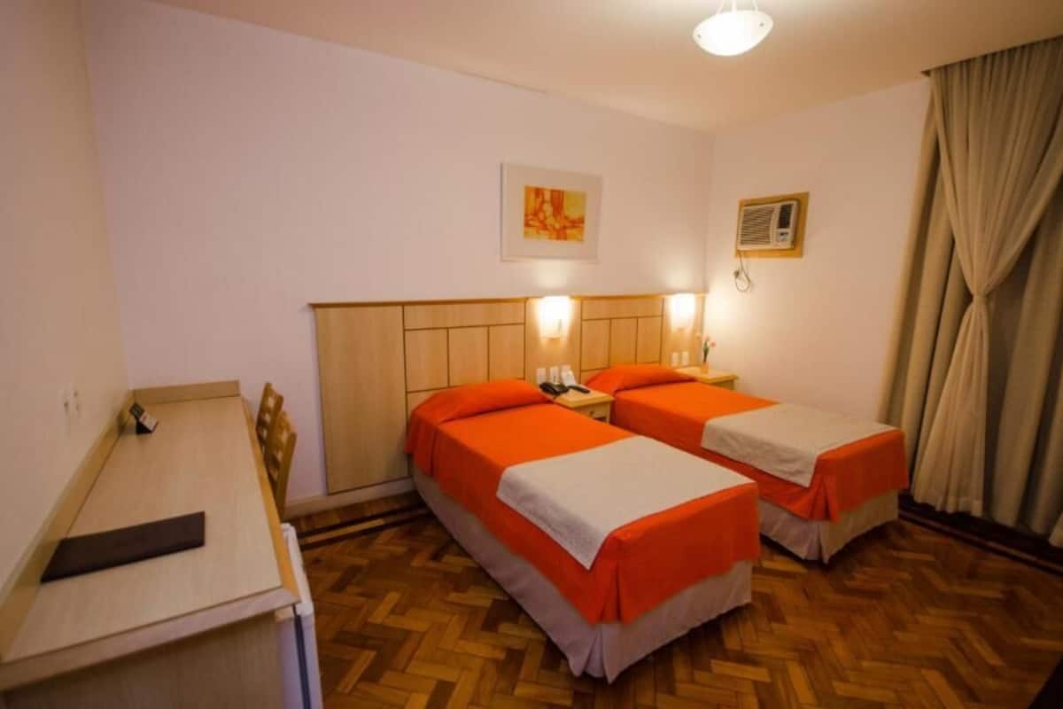 Ein Hotelzimmer mit zwei Betten, einem Schreibtisch und Holzboden.
