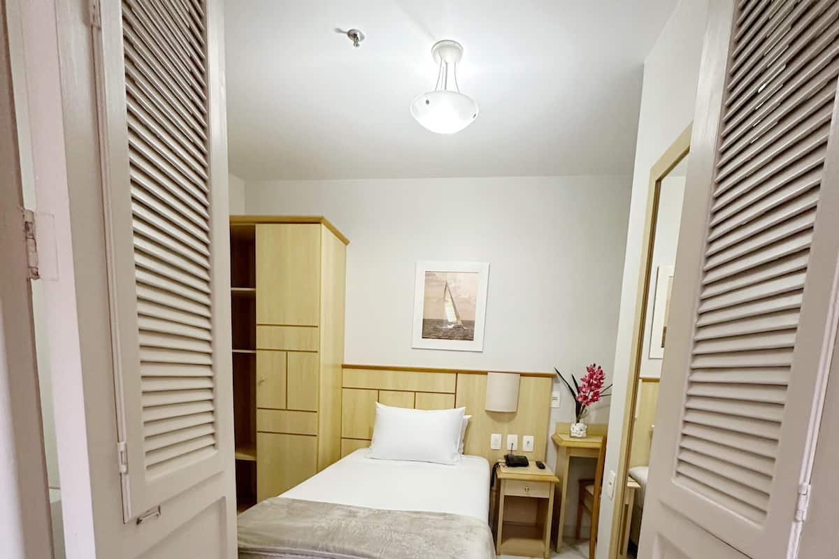 Ein Hotelzimmer mit Bett, Nachttischen, einem Kleiderschrank und einem Deckenventilator.