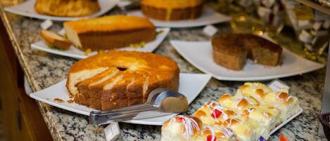 A buffet table with various cakes and pastries.