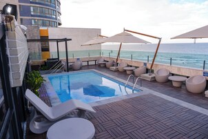 Una piscina al aire libre, sombrillas, sillones reclinables de piscina