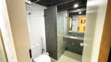A modern bathroom with a glass shower enclosure, a white toilet, and a granite countertop sink.