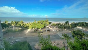 Uitzicht op de kust met een strand, palmbomen en een weg met geparkeerde auto's.