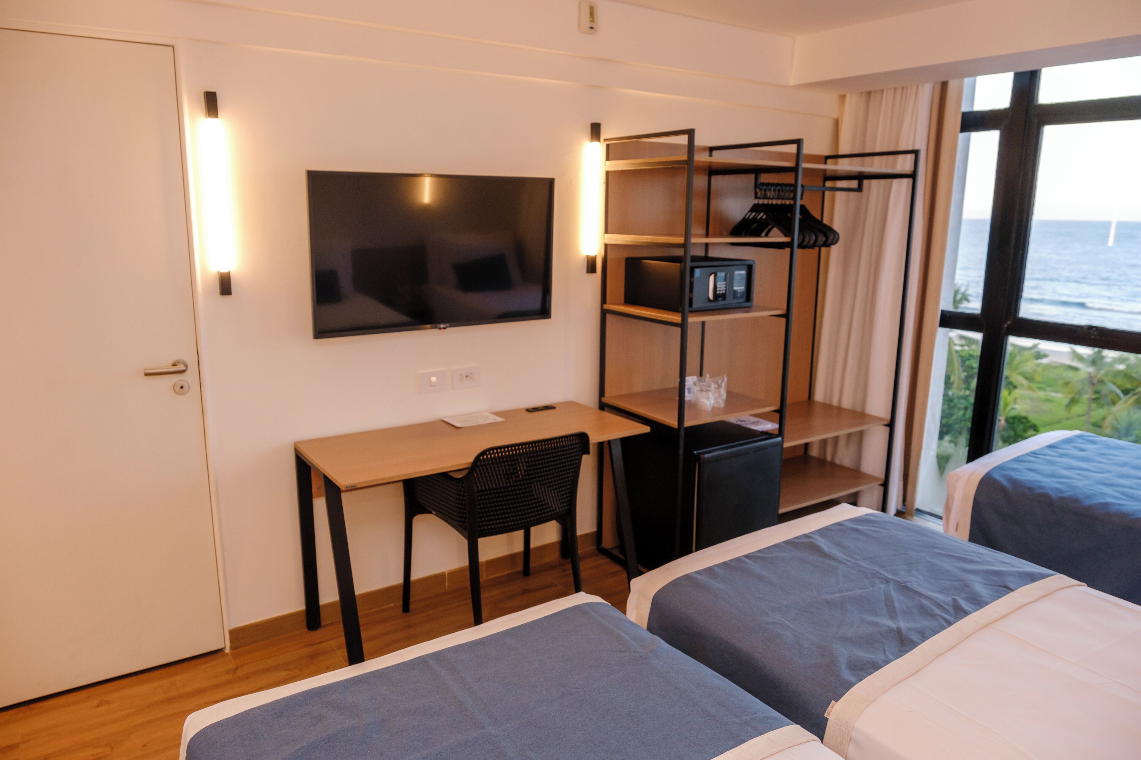 A hotel room with a TV, desk, chair, and two beds.
